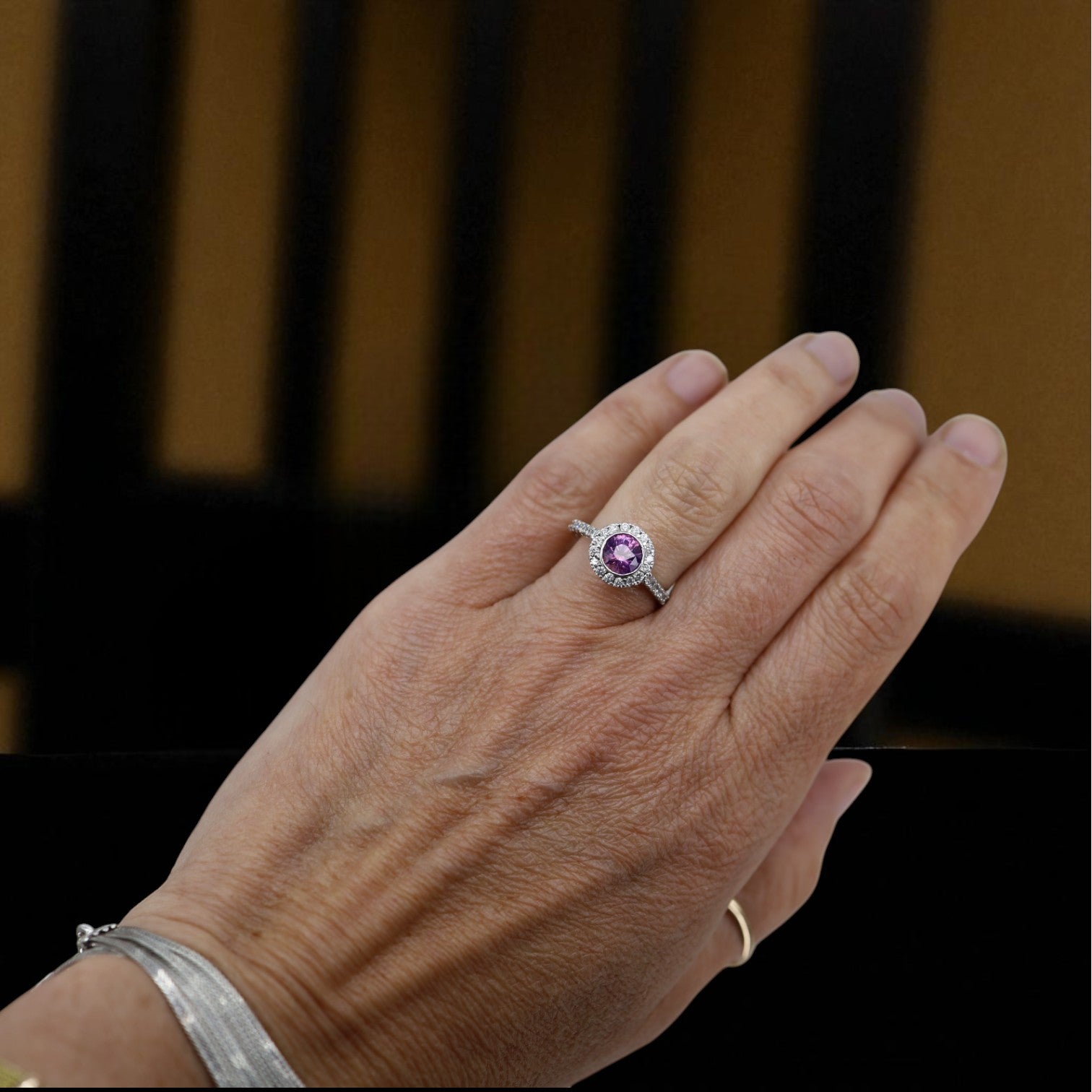 Purple sapphire halo engagement ring featuring a central purple sapphire surrounded by a diamond halo in a vintage style.