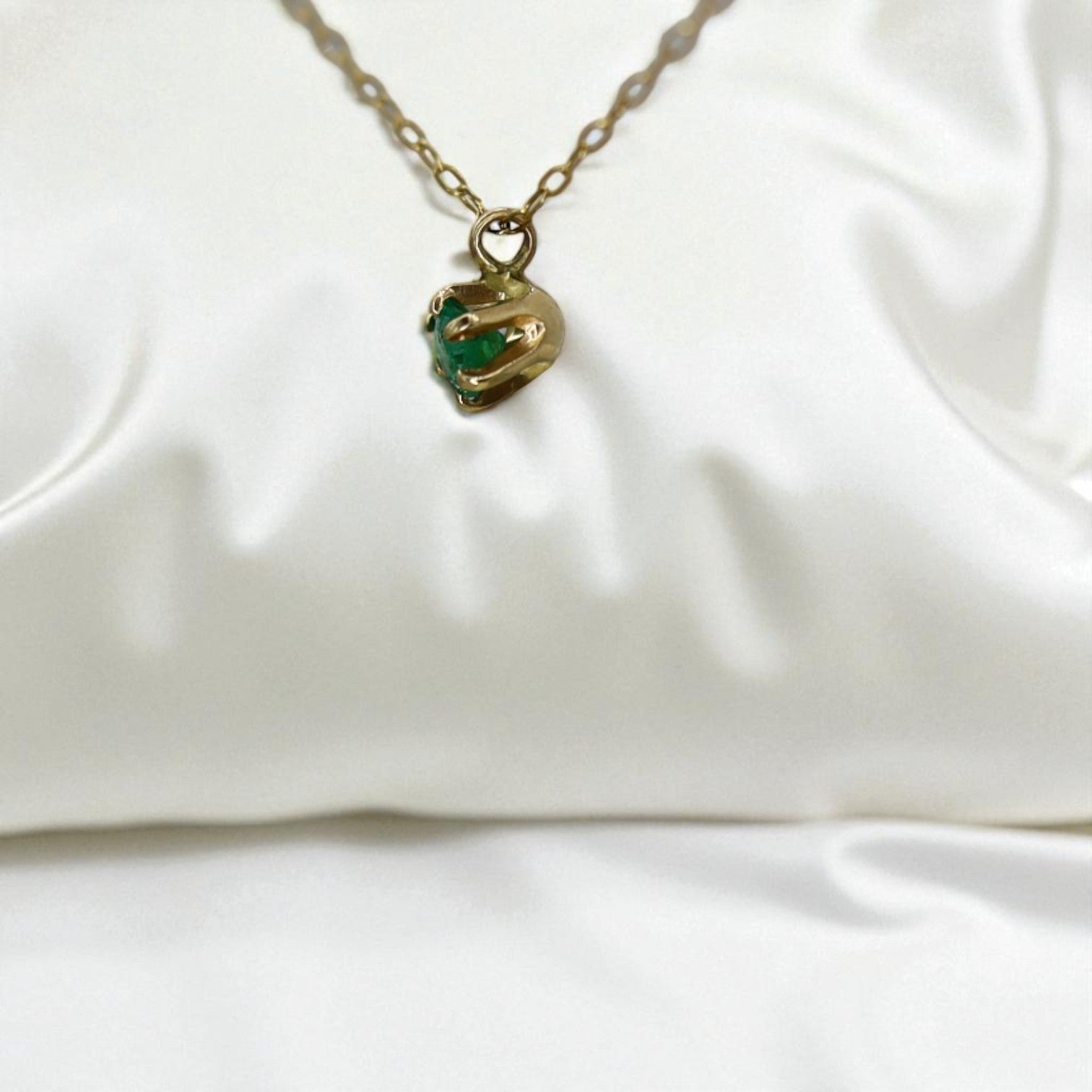 14k gold emerald pendant necklace from the 1990s featuring a vibrant green emerald set in a classic gold design.
