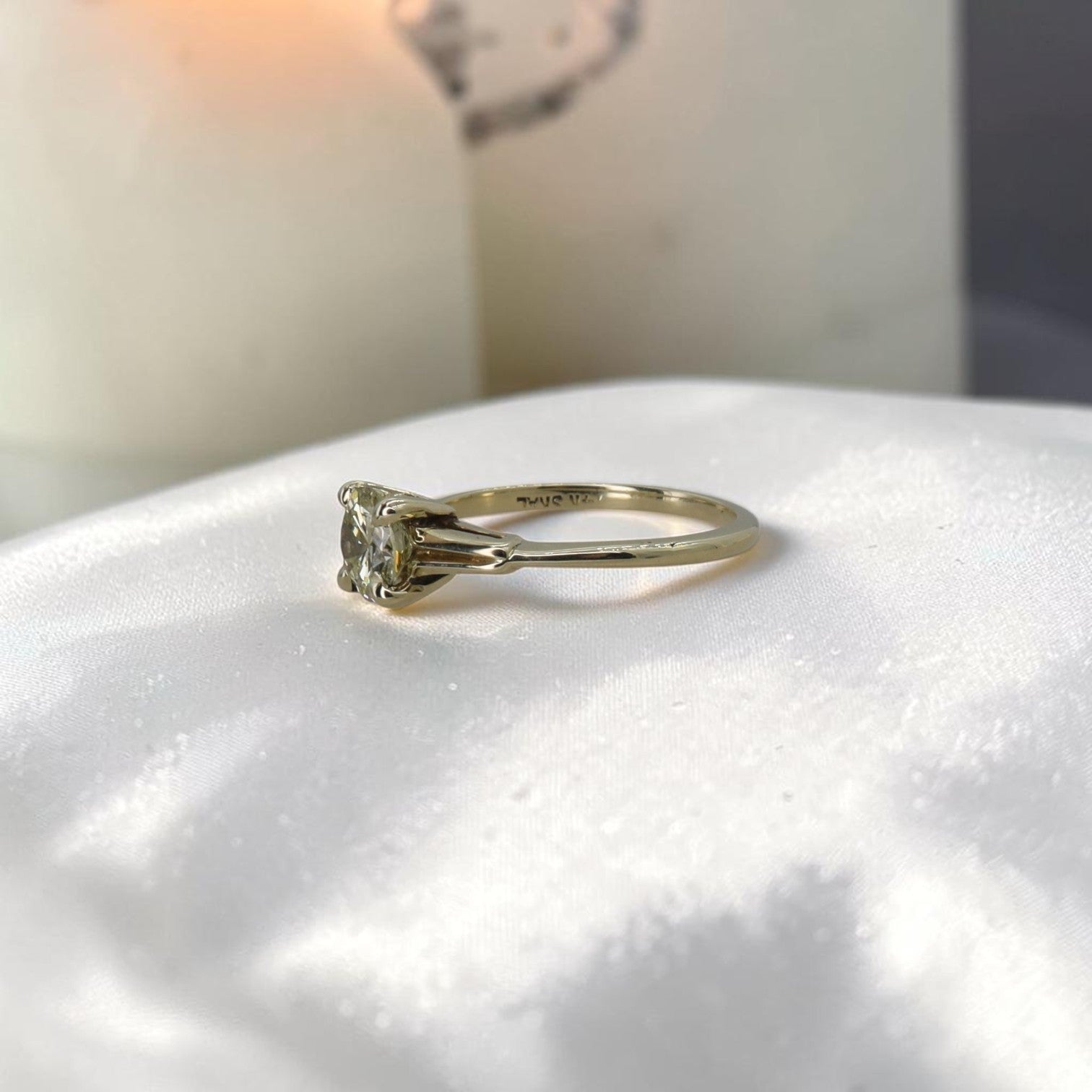 Light yellow diamond solitaire engagement ring with vintage-inspired setting, featuring a prominent diamond and intricate band details.