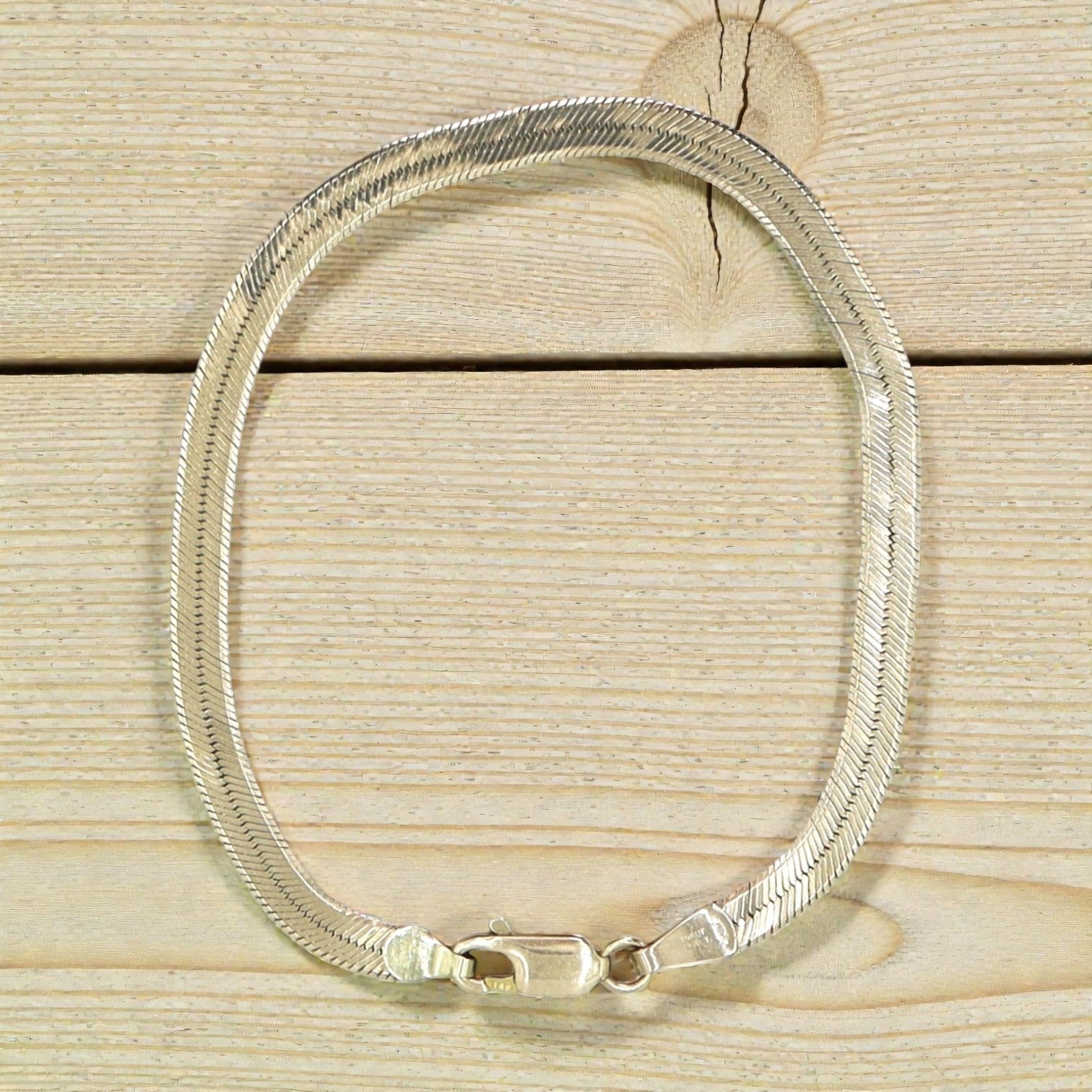 Vintage herringbone bracelet in 14k yellow gold, 4mm wide and 7 inches long, featuring a sleek and elegant design.