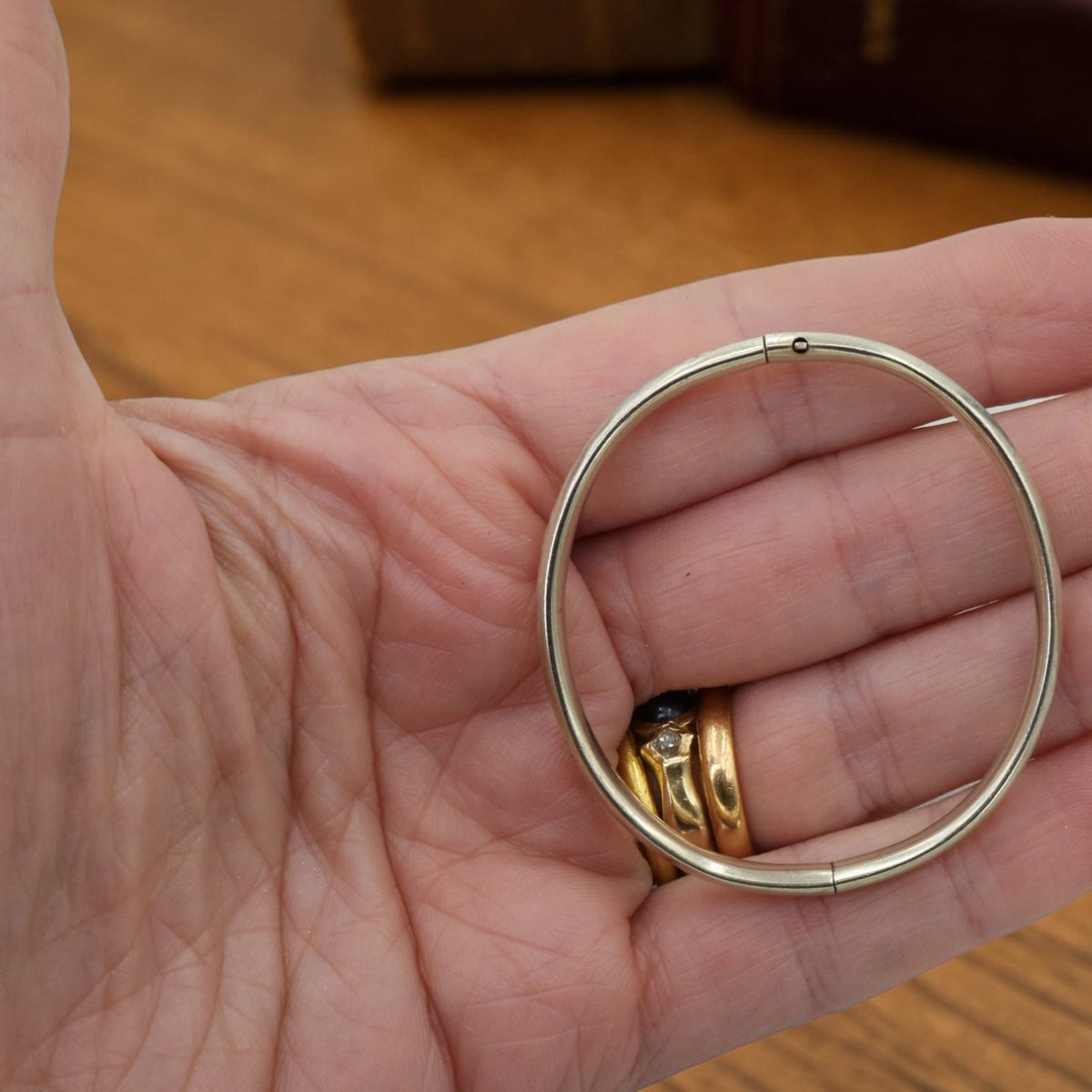 Art Deco child's hinged bangle bracelet in white gold shell, 1920s, shown in hand for scale