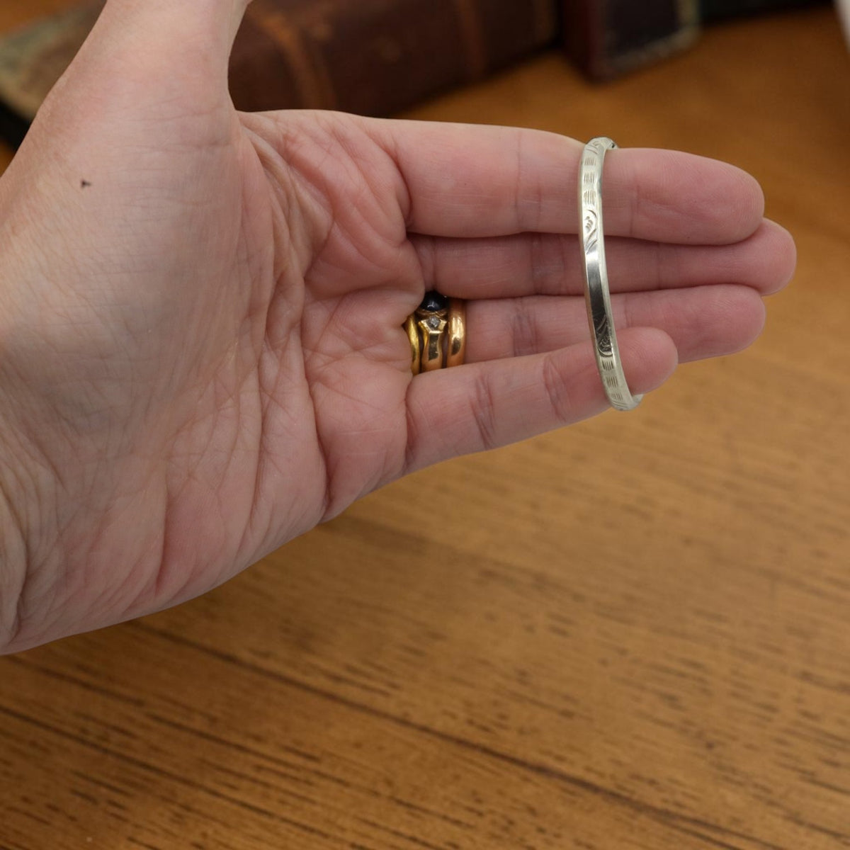 Side view of a 1920s Art Deco child's bangle bracelet showing hand engraved beveled edge