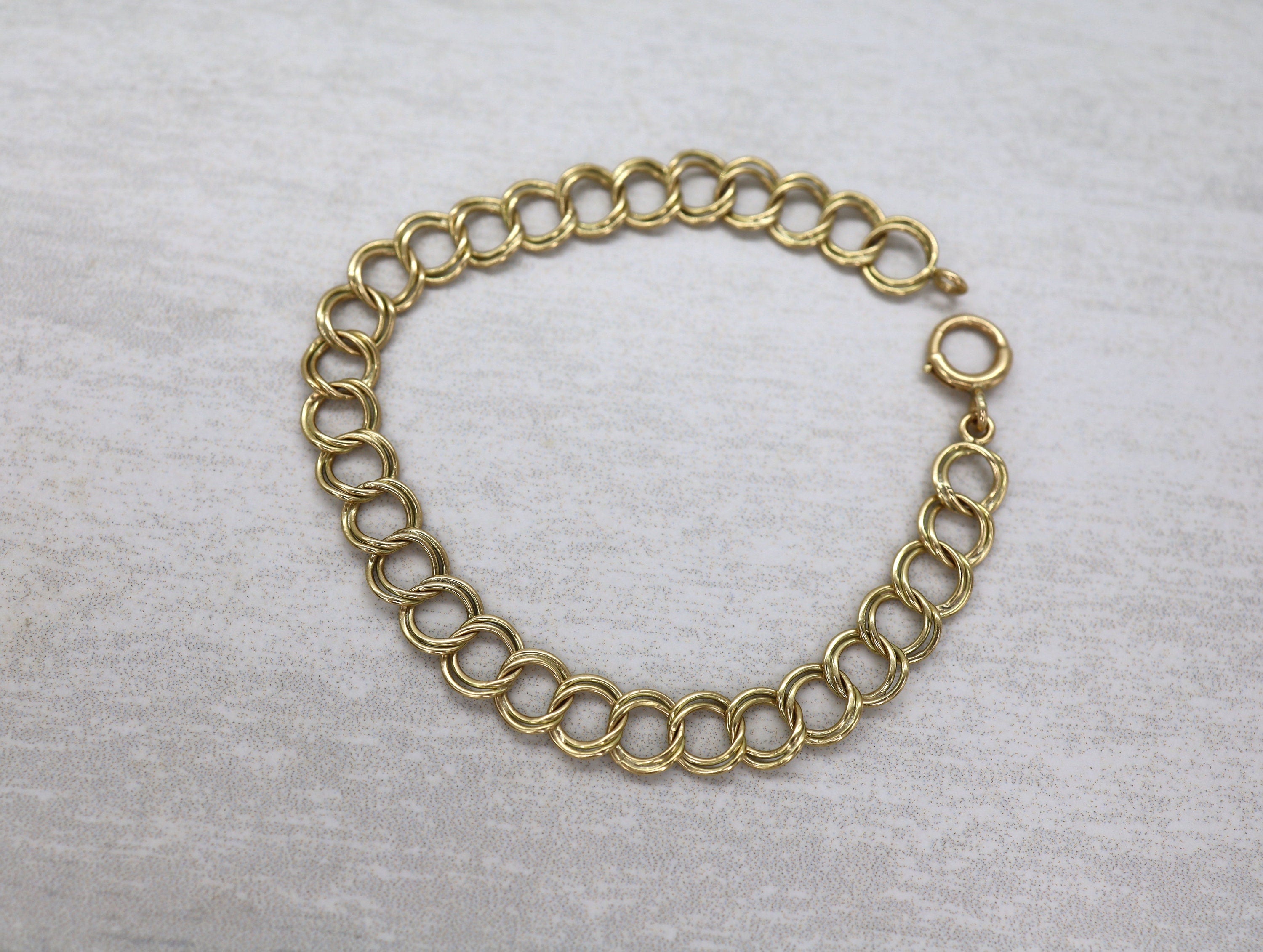 14k yellow gold charm bracelet, 7.5 inches long and 5.7mm wide, featuring detailed gold charms on a vintage-style bracelet.