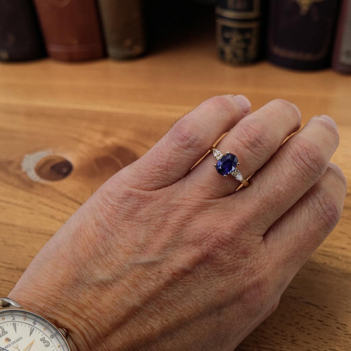 Oval sapphire and diamond ring in 14k yellow gold worn on the hand at Petra Star, Mystic CT