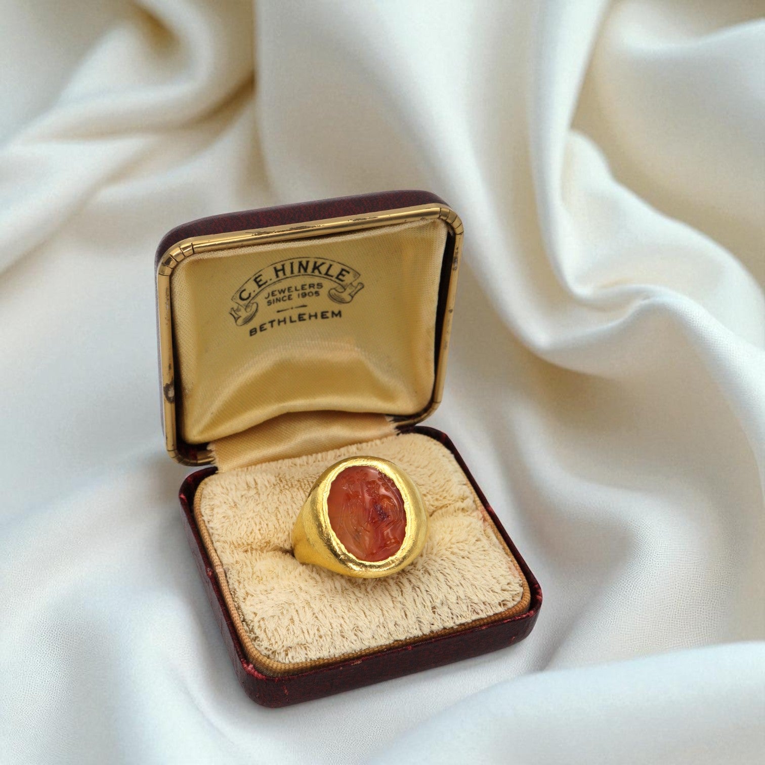 Antique carnelian intaglio ring in 22k gold with intricate vintage design, featuring a carved orange gemstone.