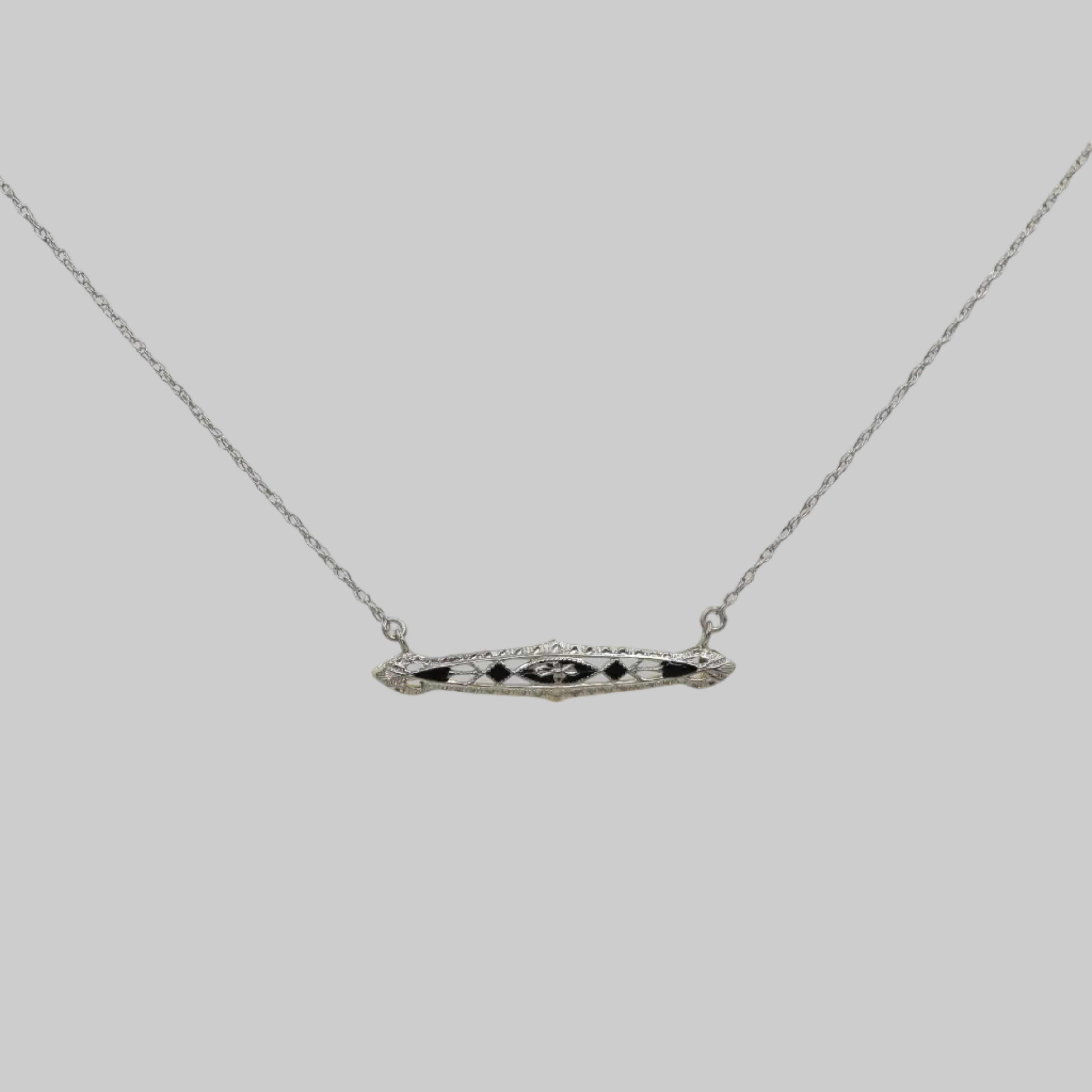 Art Deco bar necklace with black enamel in 14k white gold, featuring sleek geometric design and vintage elegance.