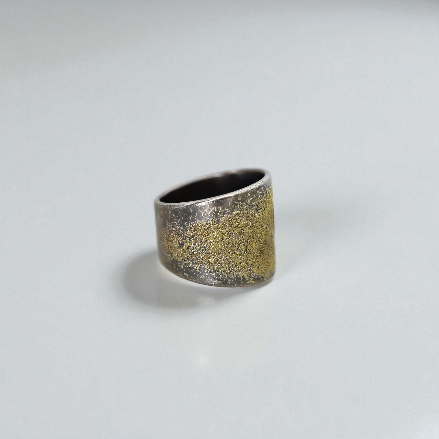 Silver ring with gold accents on a light gray background