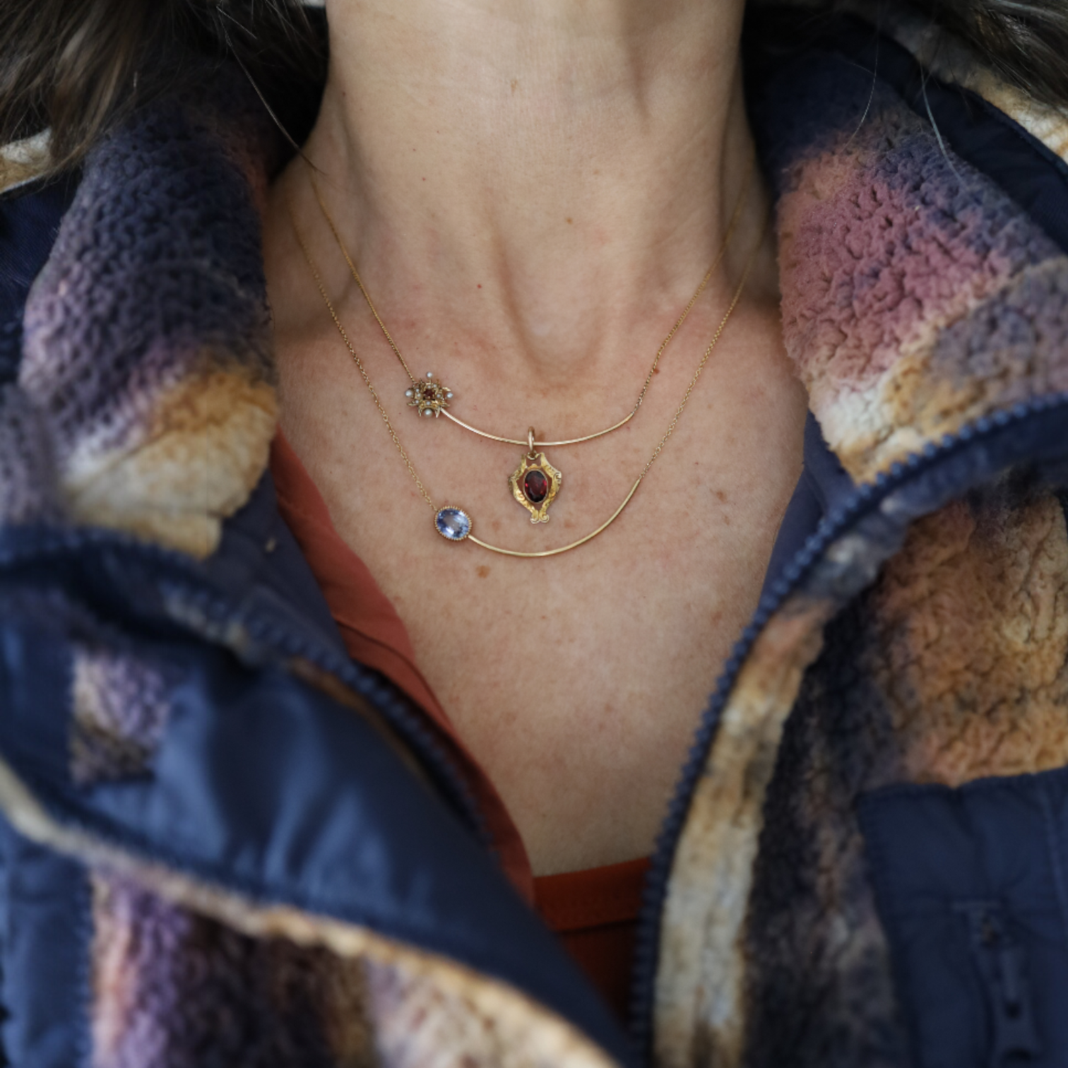 Necklace with two pendants worn by a person in a patterned garment.