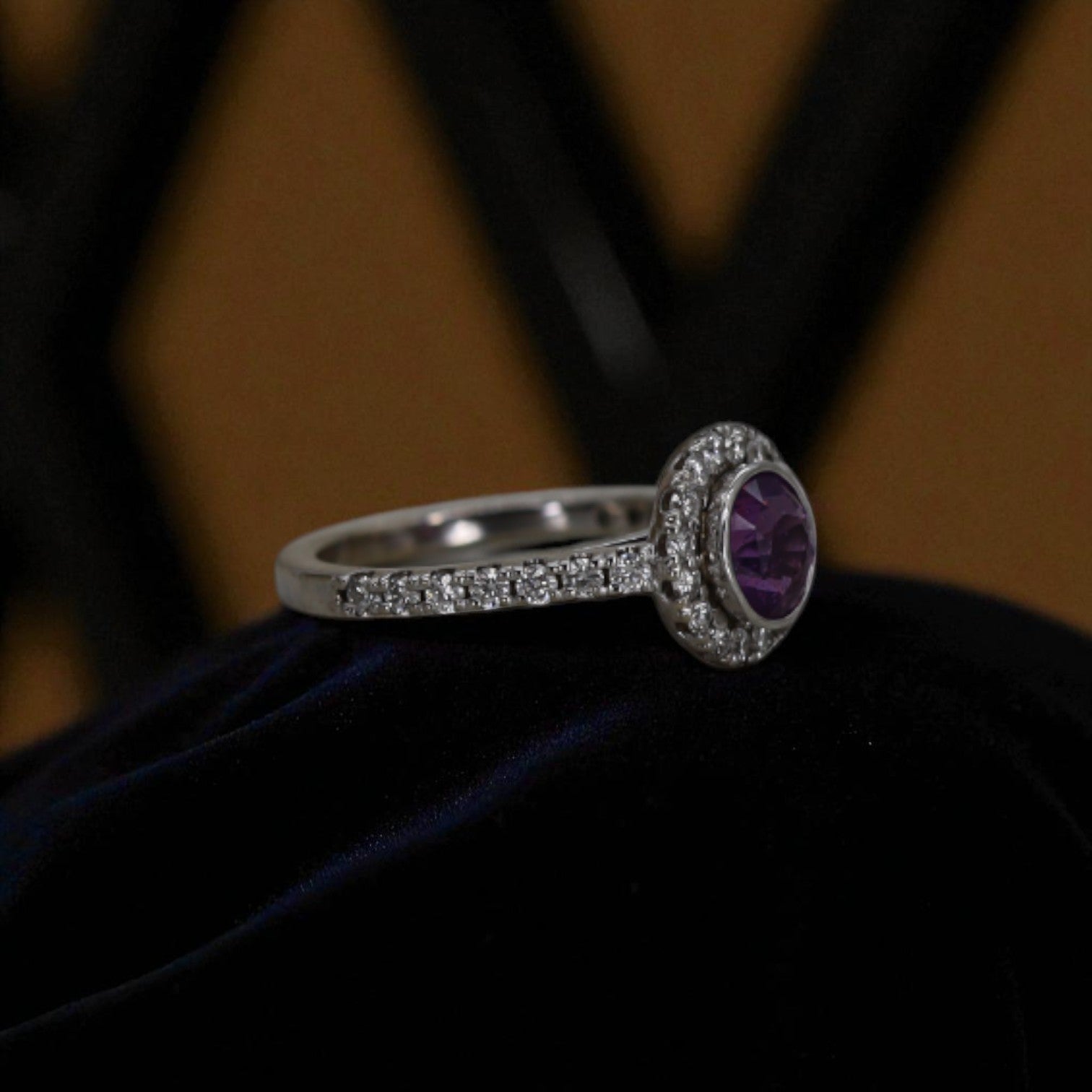 Purple sapphire halo engagement ring featuring a central purple sapphire surrounded by a diamond halo on a vintage-style band.
