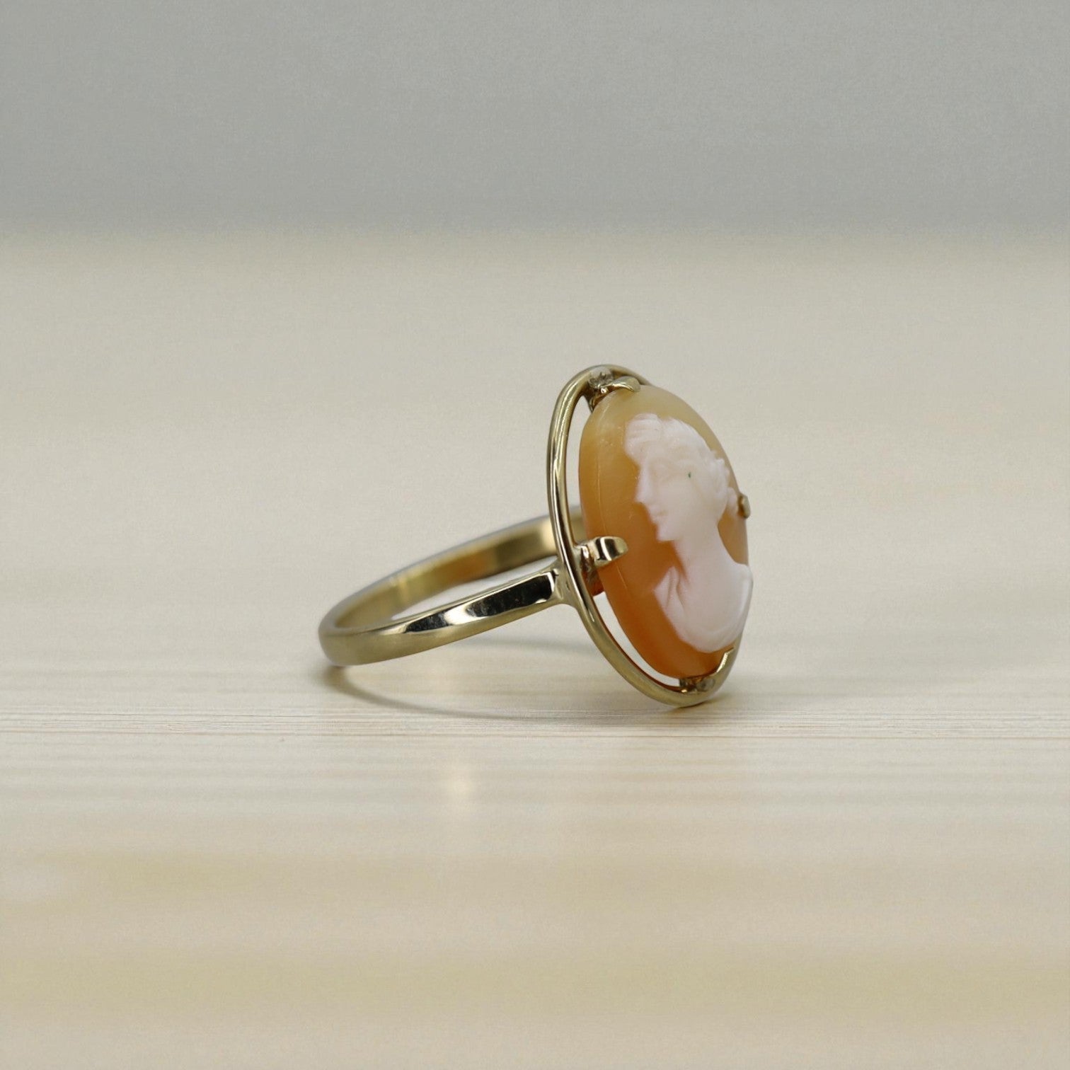 Gold ring with a cameo design on a light background