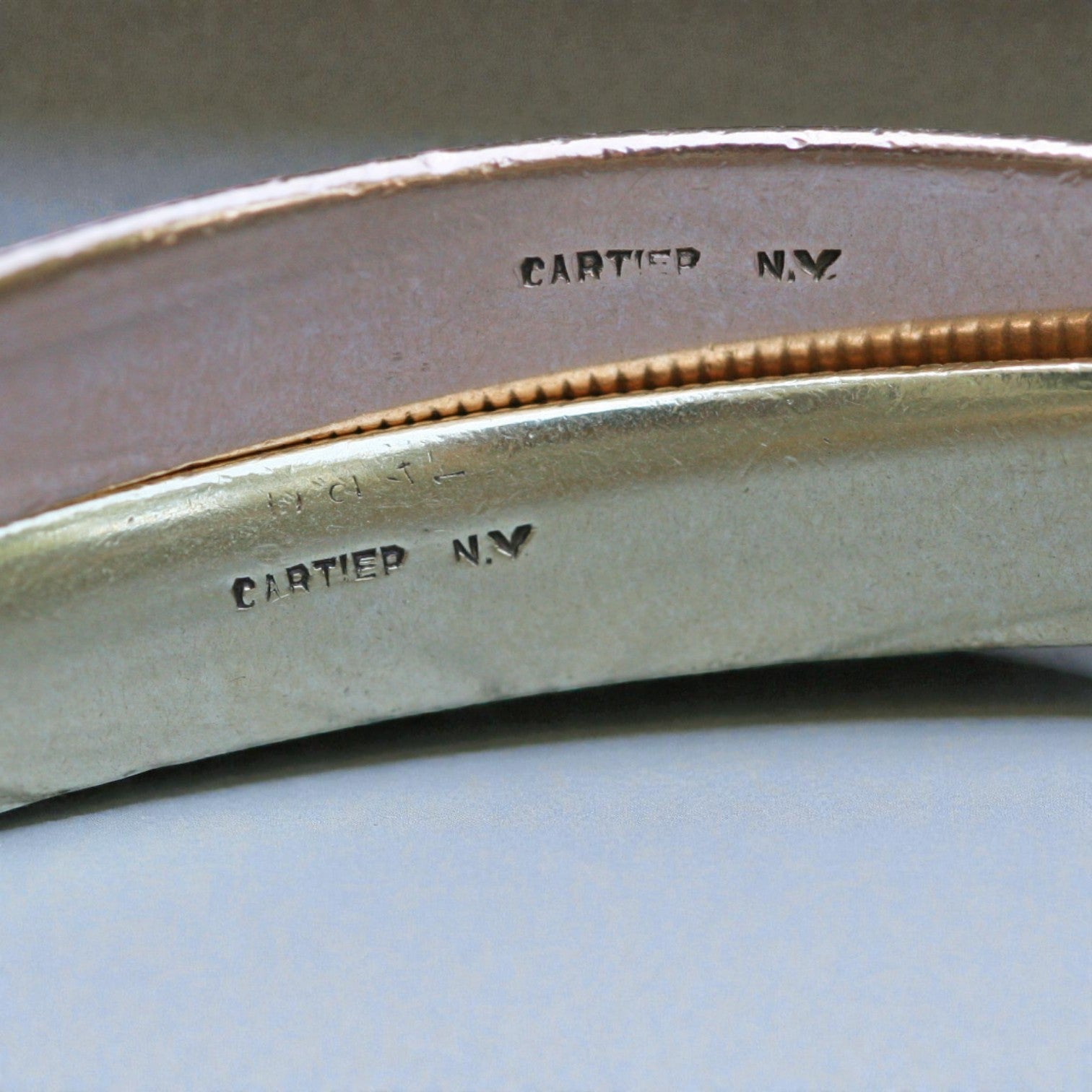 Cartier 14k gold ribbed rolling bangle bracelet with textured design, shiny finish, and smooth rounded edges.