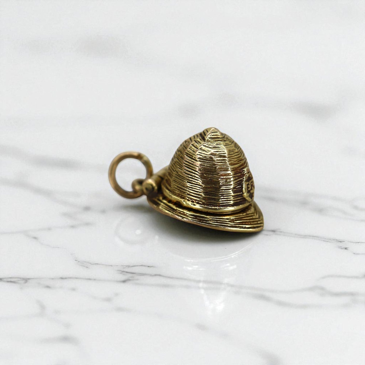 Hallmarked 9k gold fireman hat charm with detailed design, crafted by The Vintage Vault, suitable for jewelry or charm collections.