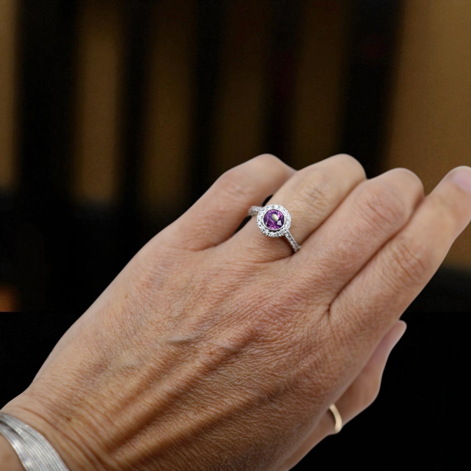 Purple sapphire halo engagement ring featuring a central purple sapphire surrounded by a diamond halo, set in a vintage-style band.
