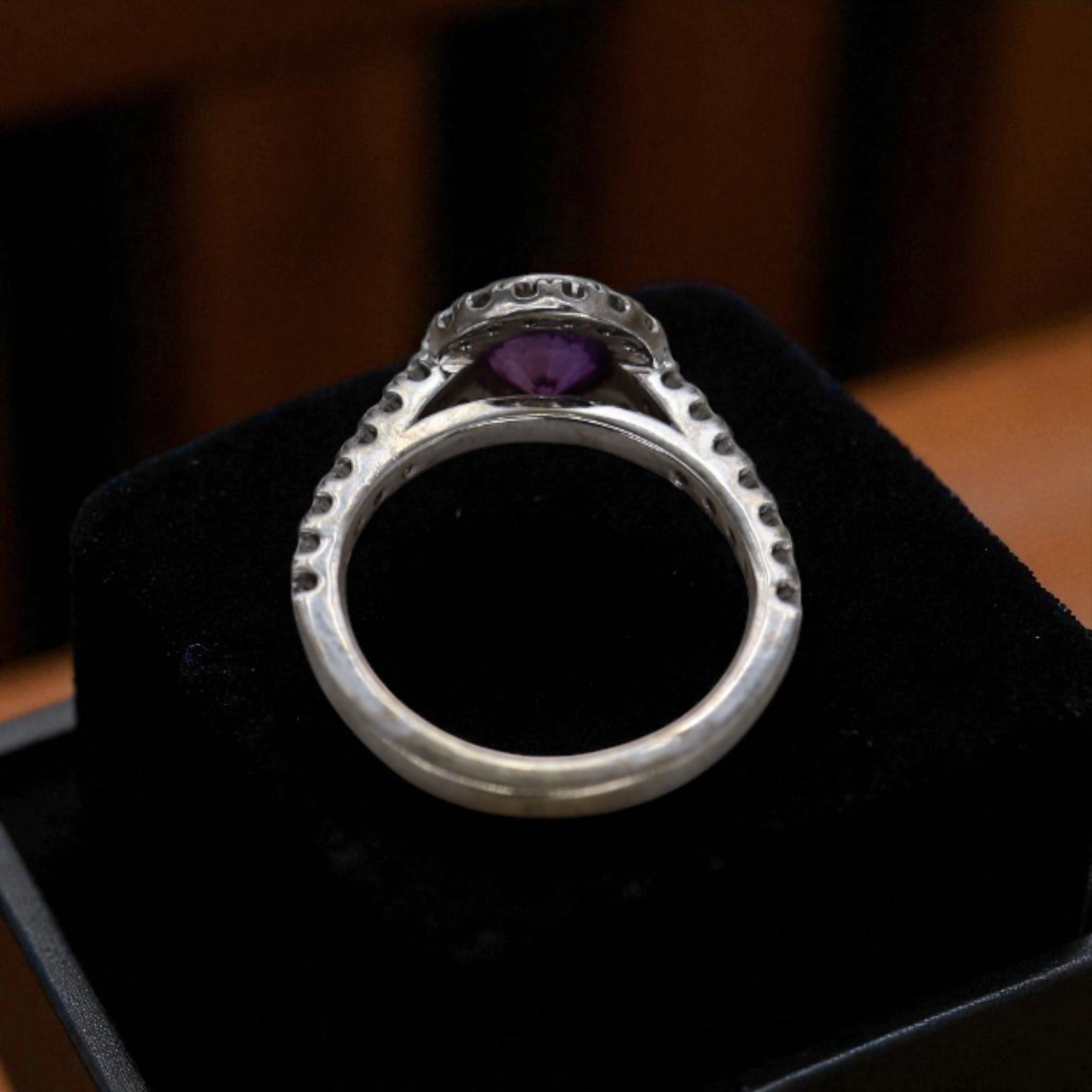 Purple sapphire halo engagement ring with a central purple sapphire surrounded by a diamond halo, set in a vintage-style band.