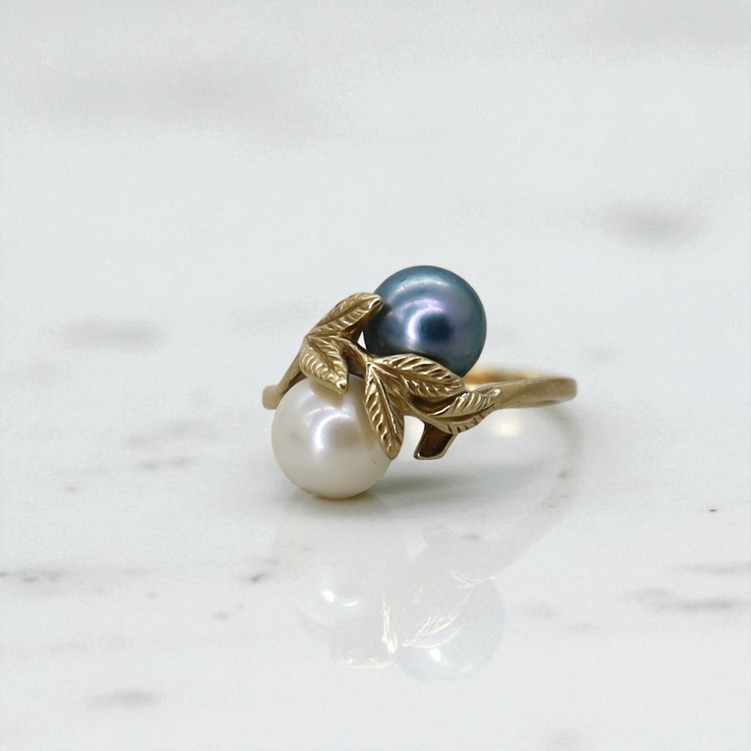 Vintage 14k gold leaf ring featuring black and white pearls, showcasing intricate design and elegant craftsmanship.
