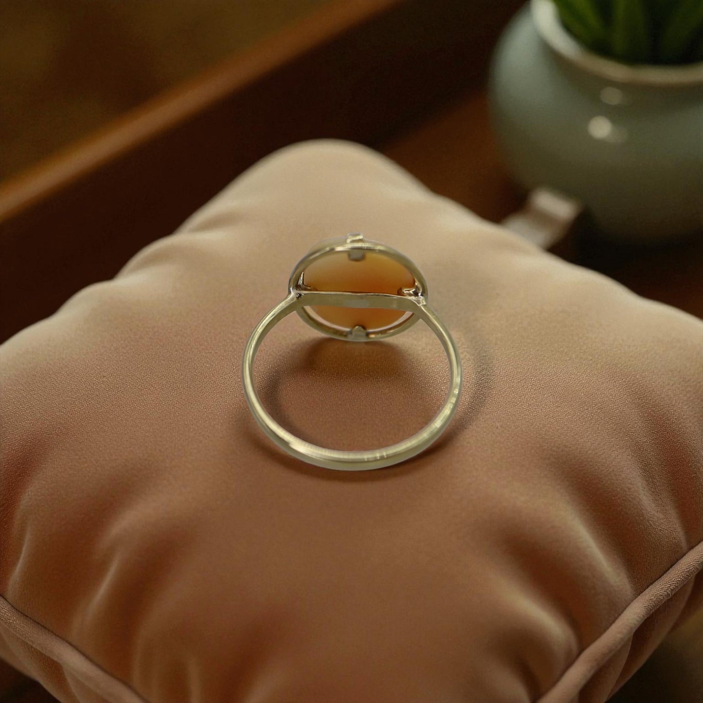 Silver ring holder on a beige cushion with a blurred background