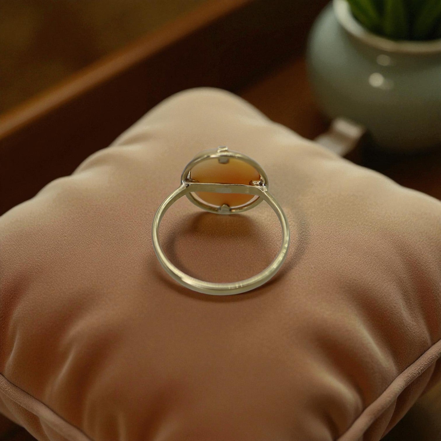 Silver ring holder on a beige cushion with a blurred background