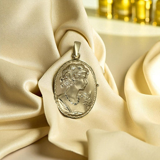 Gold cameo pendant on beige fabric with blurred gold background