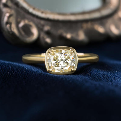 Cushion cut diamond solitaire engagement ring in 14k gold with east-west setting, featuring a classic vintage style.