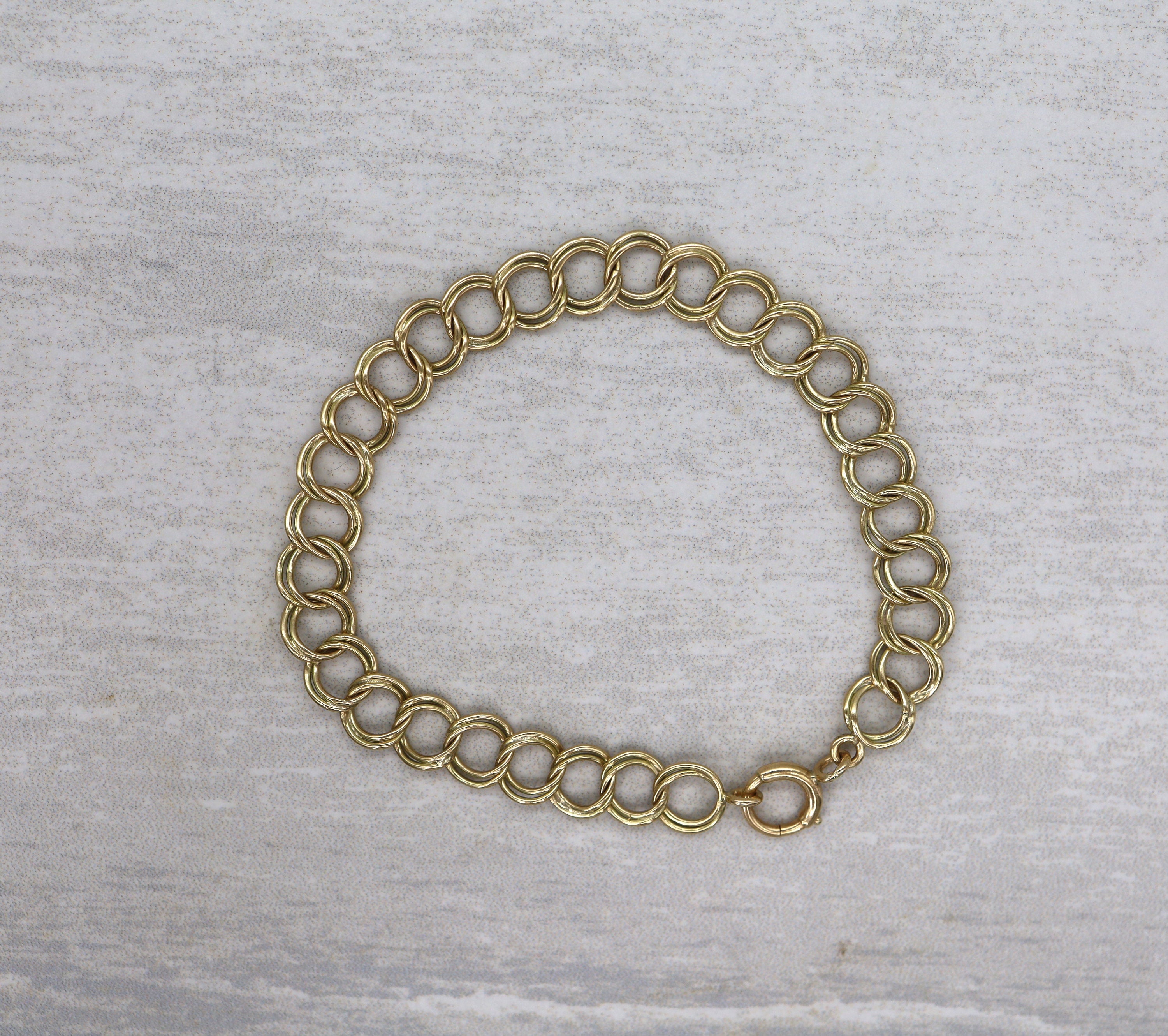 14k yellow gold charm bracelet, 7.5 inches long and 5.7mm wide, featuring intricate details and a polished finish.