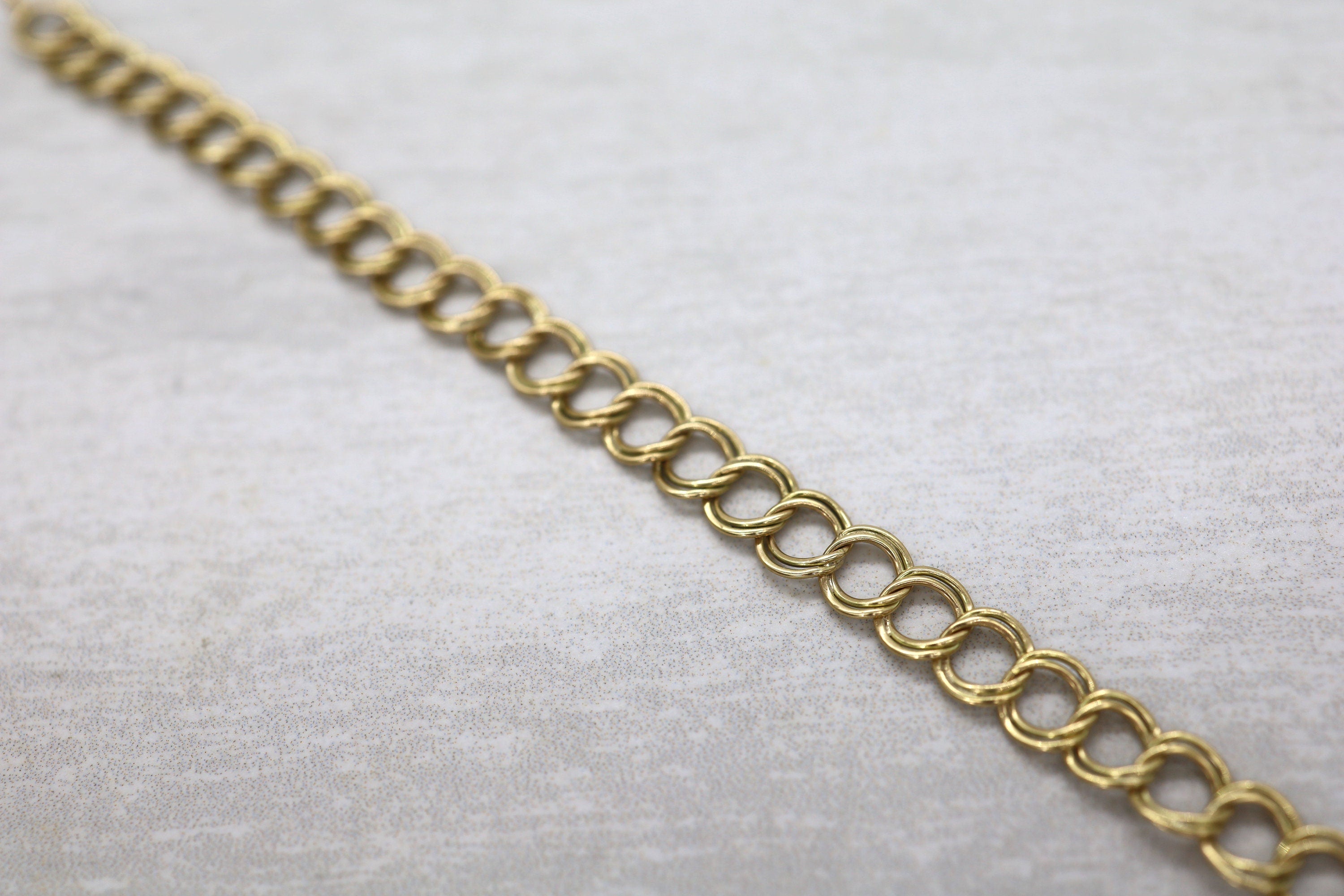 14k yellow gold charm bracelet, 7.5 inches long and 5.7mm wide, featuring intricate design details and a secure clasp.