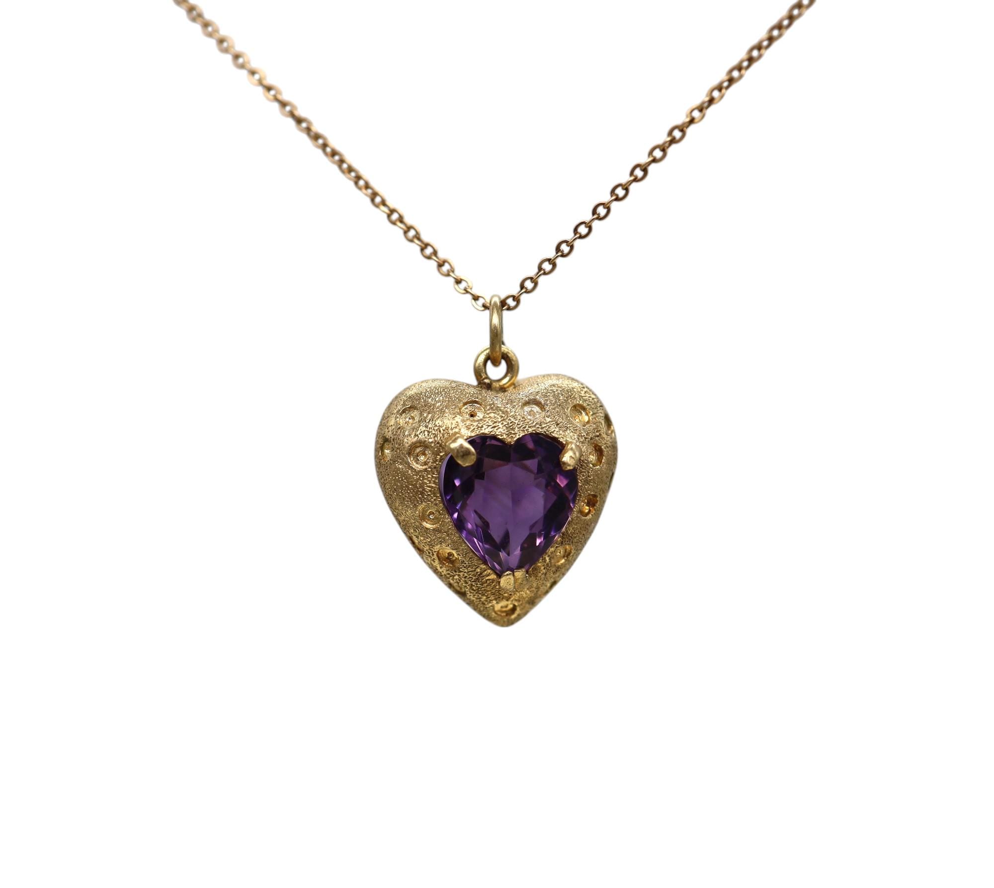 14K gold amethyst puffy heart pendant with vintage design, featuring a vibrant purple gemstone hanging from a gold chain.