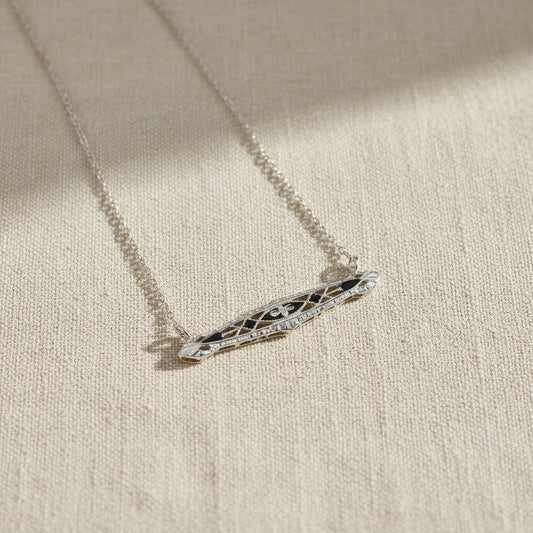 Art Deco  necklace with a decorative pendant on a beige fabric background