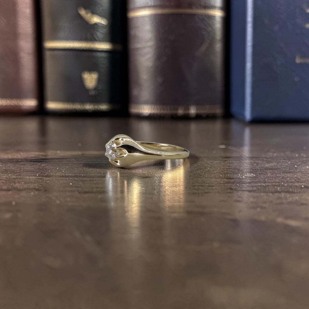 Profile view of a 14k yellow gold Belcher ring showing the buttercup claws holding the diamond low to the band