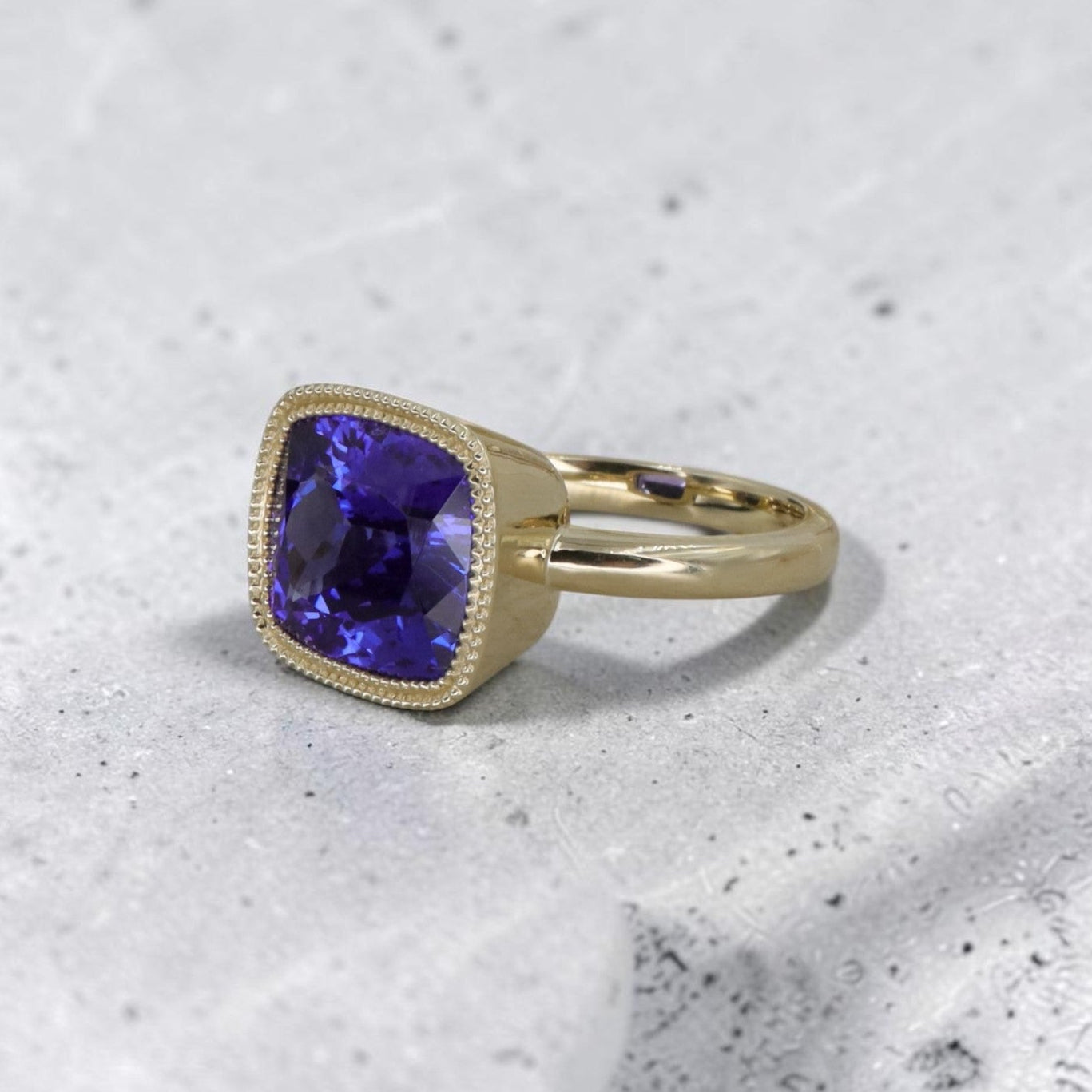 14k yellow gold ring with a cushion-cut tanzanite gemstone, custom-made Petra Star jewelry featuring elegant gemstone setting.