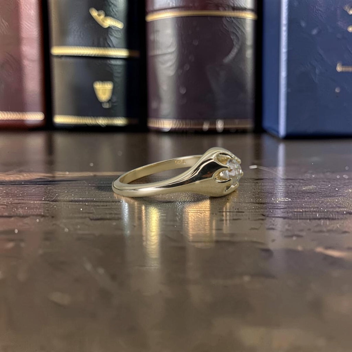 Three-quarter side view of a low-profile 14k yellow gold Belcher ring with an antique Old Mine cut diamond