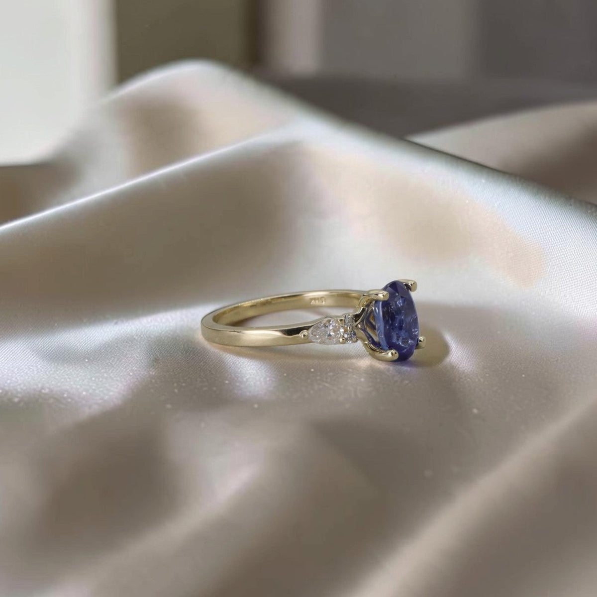 Side profile of oval sapphire and diamond ring in 14k yellow gold showing four-prong setting