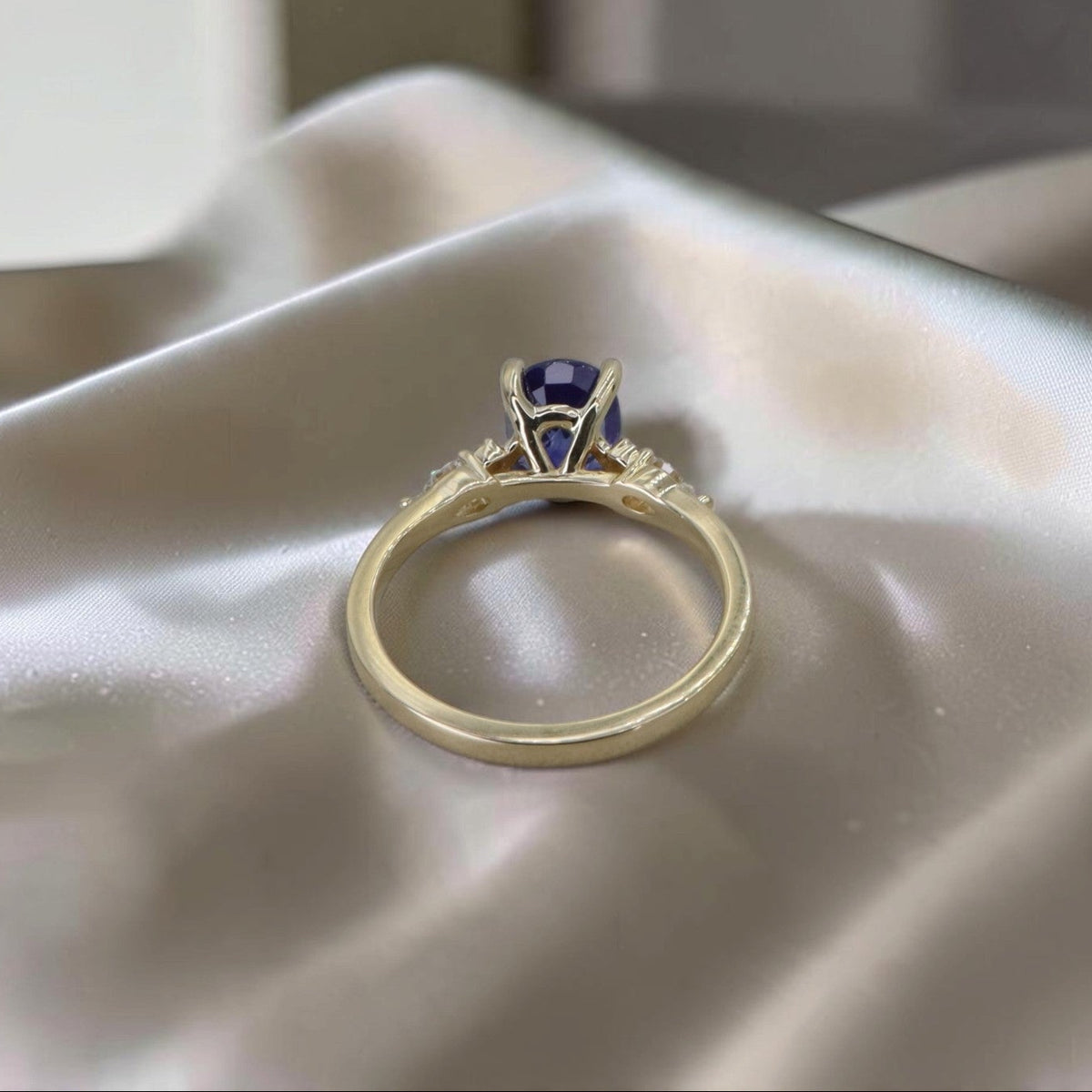 Back view of oval sapphire and diamond ring showing the open basket setting and 14k yellow gold band