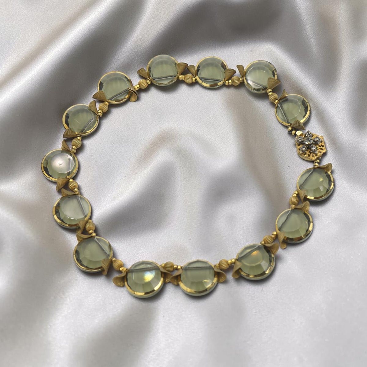 Full view of 1950s Miriam Haskell necklace with fourteen gold-edged smoky quartz discs on ivory satin